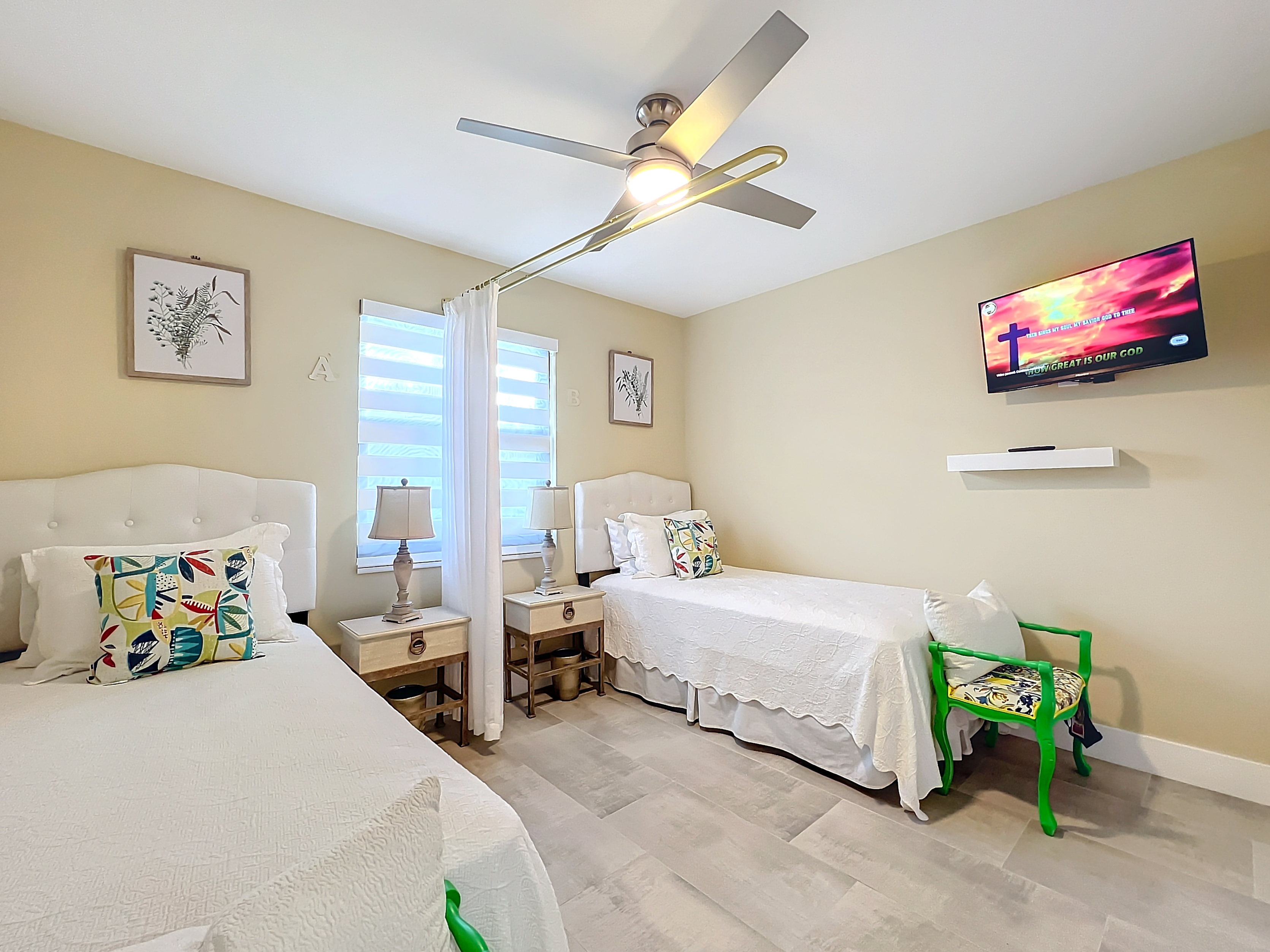 Deluxe shared resident suite with color-coordinated bedding, armchair, and wall-mounted TV at Abundant Care Residence in Wellington, FL