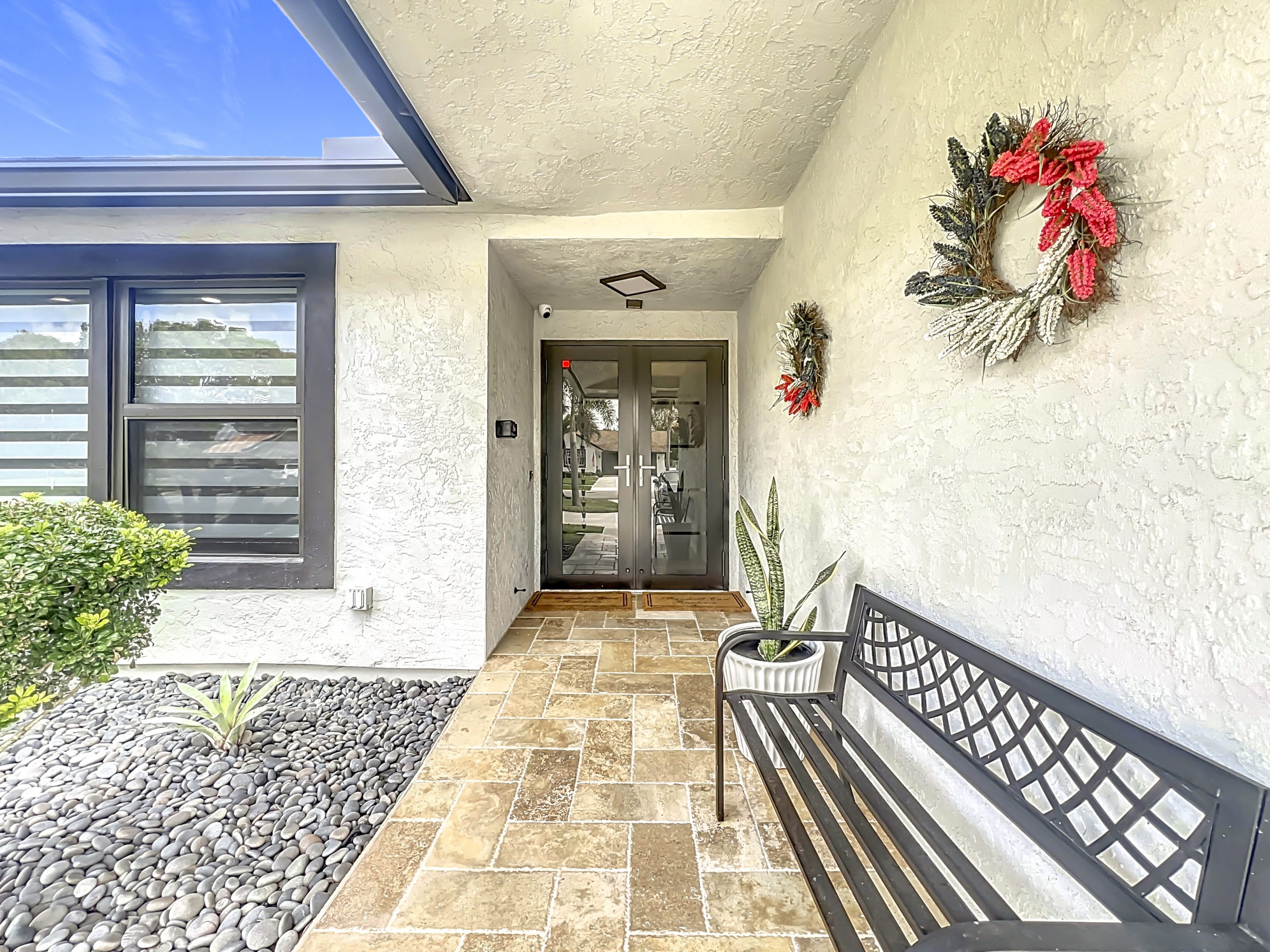 Charming front entrance porch with double glass doors and stone pathway at Abundant Care Residence in Wellington, FL