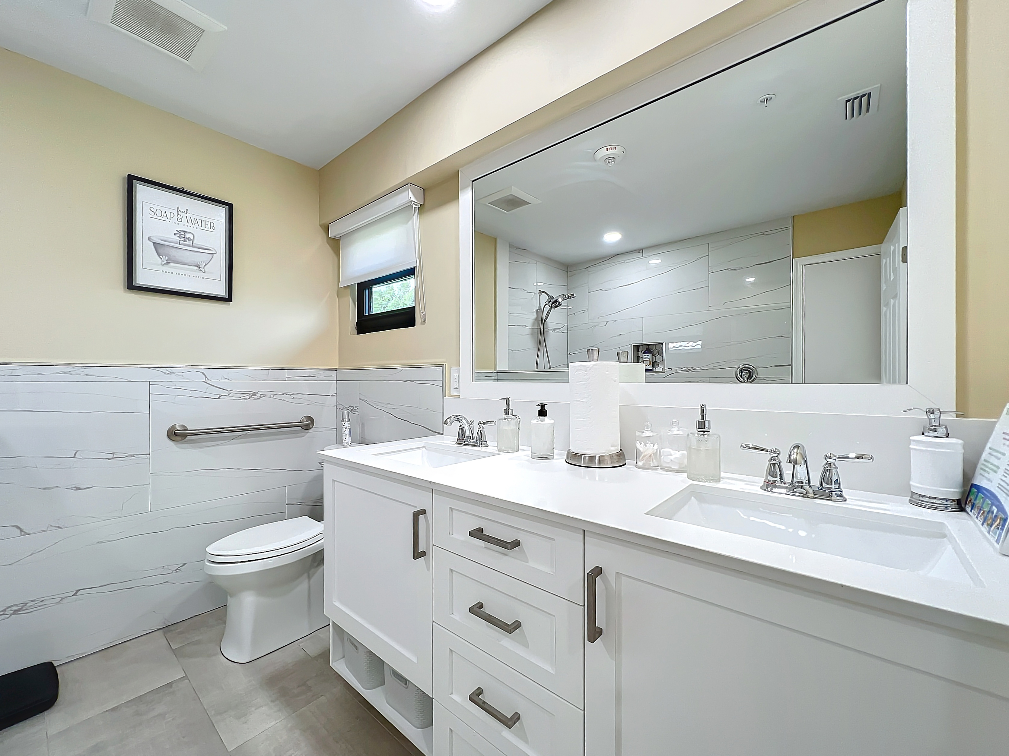 Modern wheelchair-accessible bathroom suite with a double vanity and safety grab bars at Abundant Care Residence in Wellington, FL