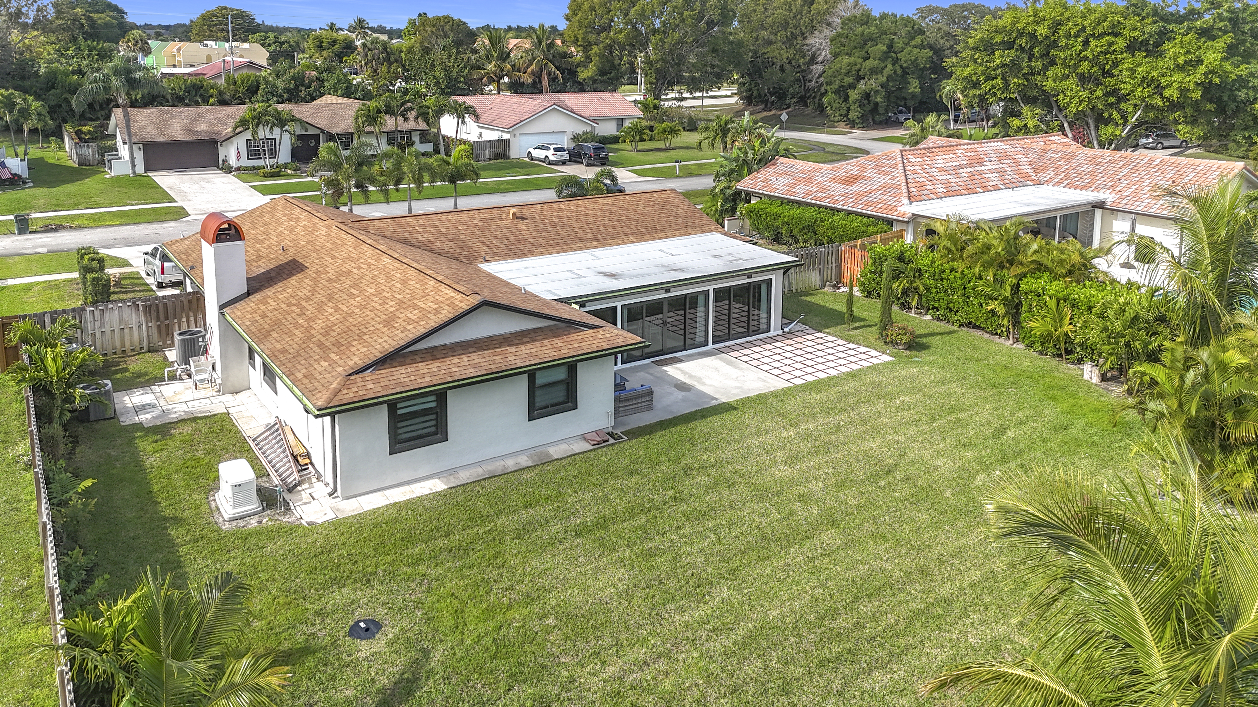 Aerial drone view of the Abundant Care Residence facility showing the sprawling backyard and lush green lawn in Wellington, FL